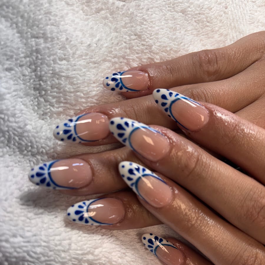 Almond nails with hand-painted blue-and-white floral French tips by Bluerose Natural Nail